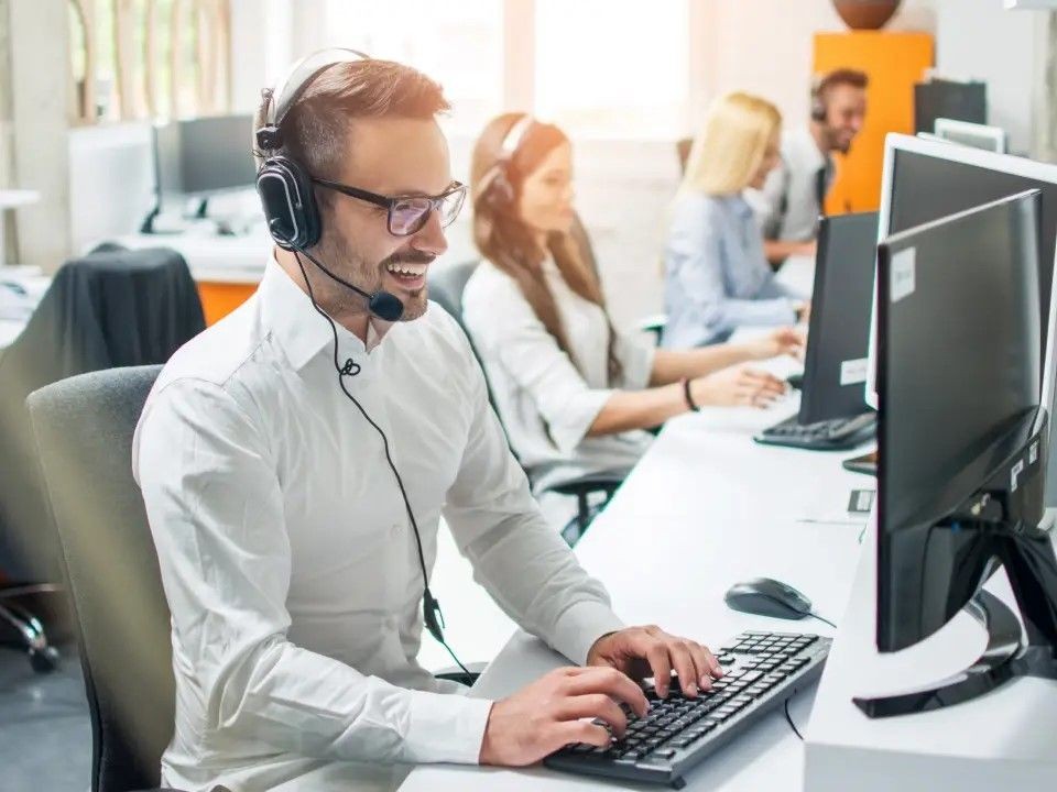 Customer support team working on computers with headsets in a modern office setting.